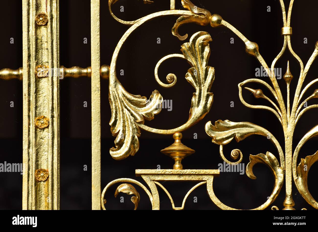 Eine Nahaufnahme von goldverzierten Metallarbeiten an Palasttoren vor schwarzem Hintergrund Stockfoto