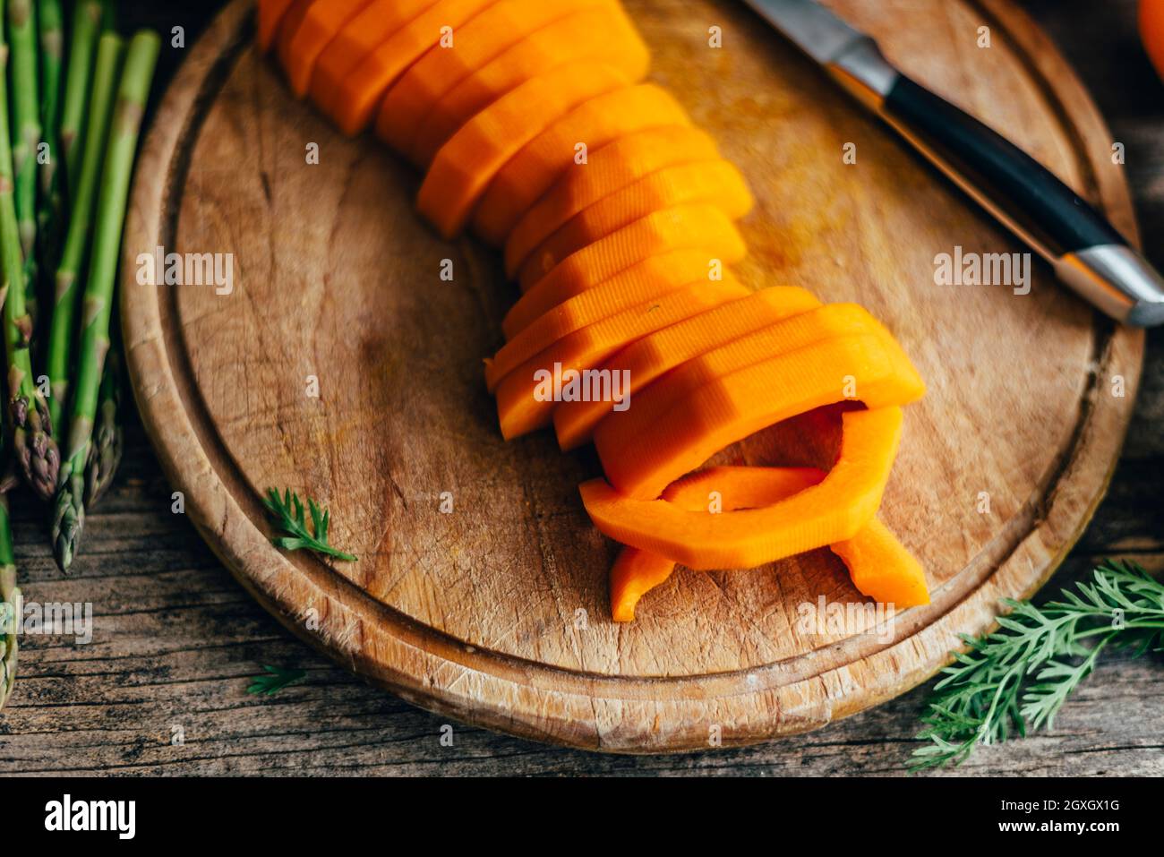 Butternut-Squash-Zubereitung auf einem hölzernen Küchentisch. Kochen von Speisen zum traditionellen Danksagebungsessen. Herbstrezept für Veganer mit Kürbisvege Stockfoto
