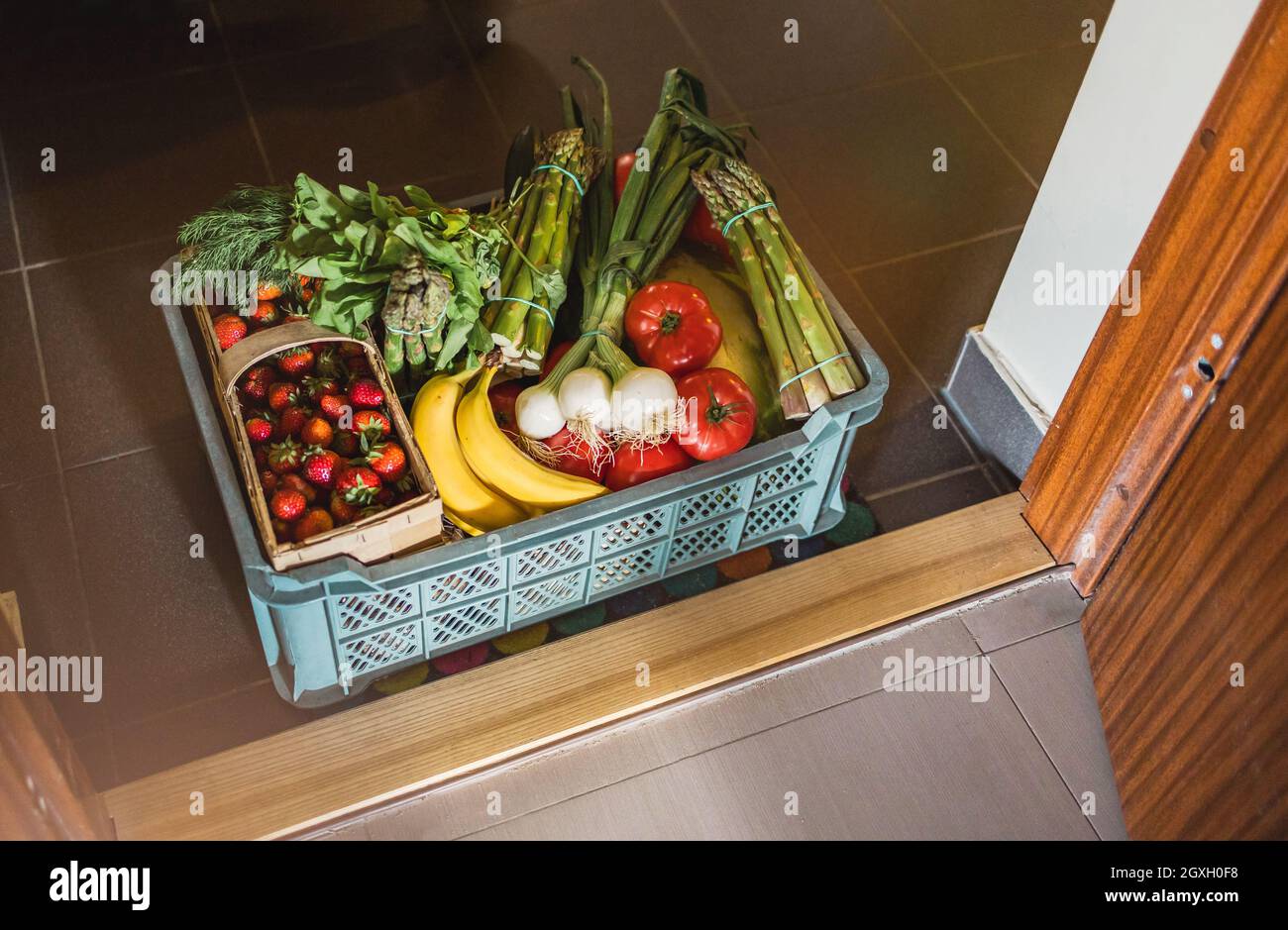 Obst- und Gemüselieferkarton vor einer Tür zur Wohnung Stockfoto
