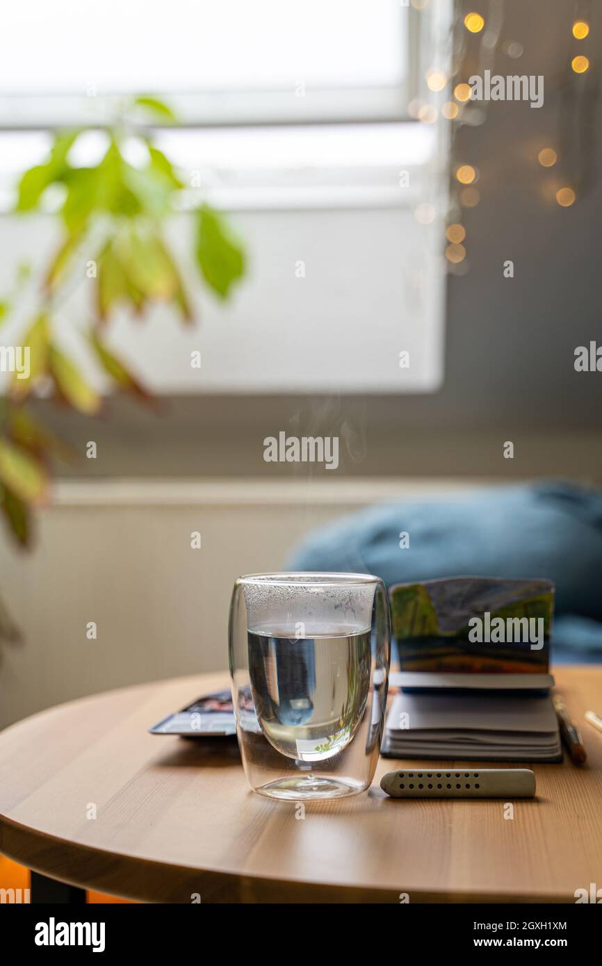 Glas Tasse heißes Wasser auf Holztisch mit Aquarell Zeichnung in Papier-Notizbuch Stockfoto