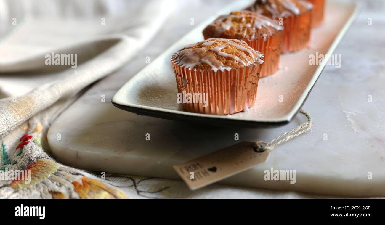 Süßes Gebäck, Puderzucker, süße Kuchen auf Marmor. Tasse Kuchen auf einem Küchentisch. Vintage Süßigkeiten, Vintage Tischdecke mit Stickerei auf Leinenstoff Stockfoto