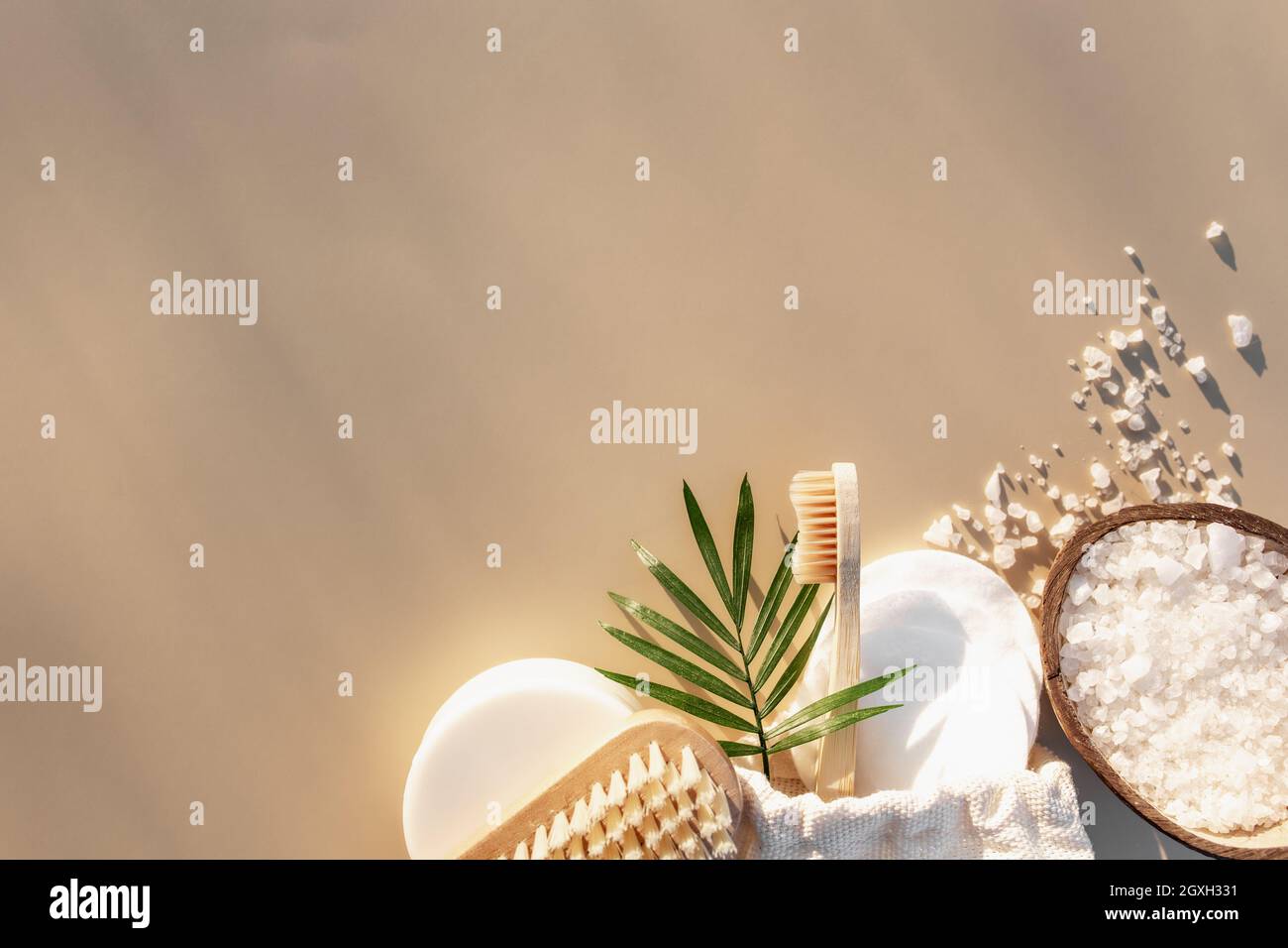 Bad-Accessoires flach auf beigem Hintergrund mit Sonnenschatten-Effekt. Gesundheitskonzept, Zahnbürste aus Holz, Fußbürste, Wattepads, Seife. Eco, Null Stockfoto