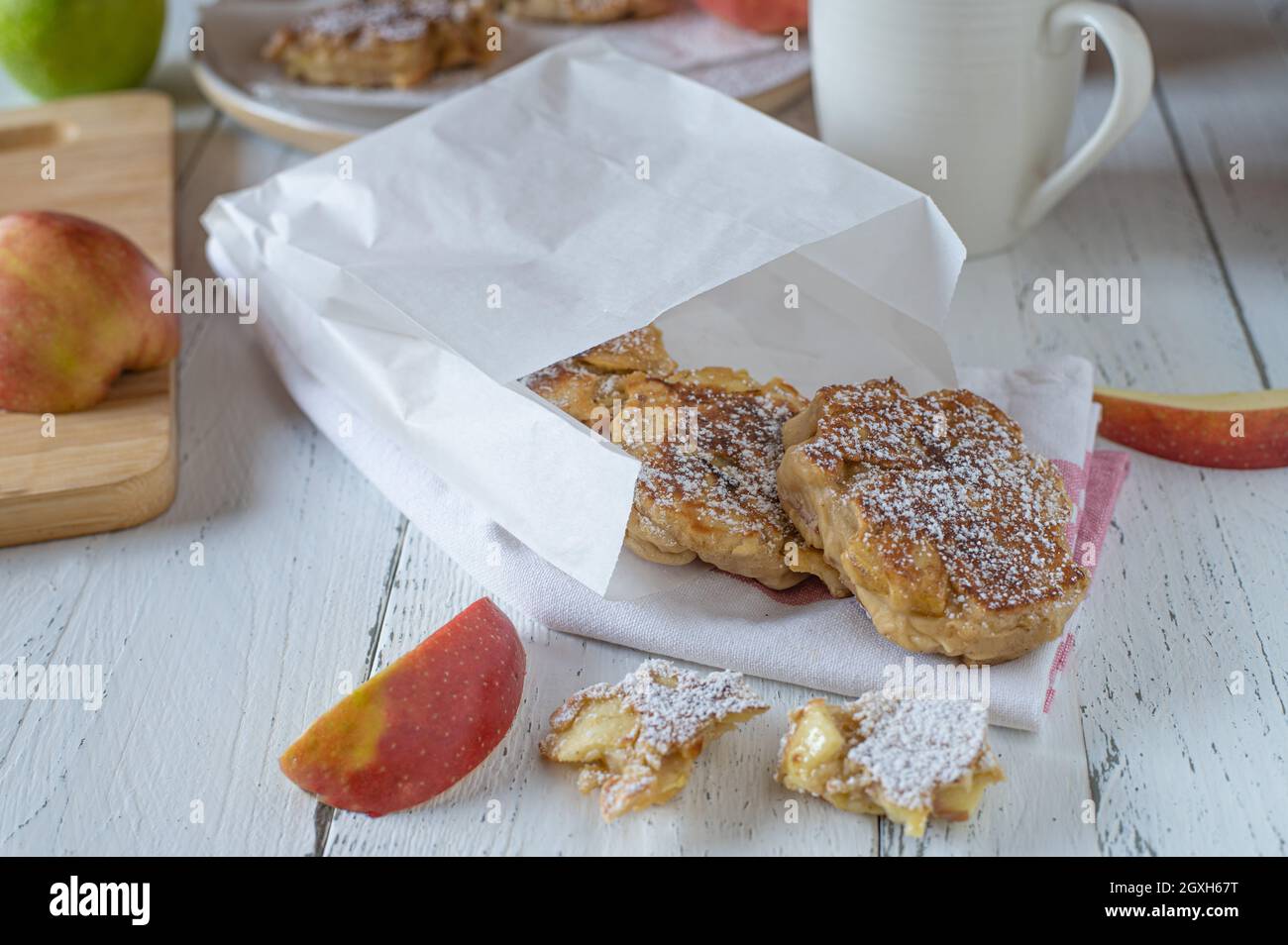 Apfelpfannkuchen für unterwegs. Frische und hausgemachte Pfannkuchen in der Pfanne mit Vollkornmehl und frischen Äpfeln. Serviert in einer Papiertüte. Stockfoto