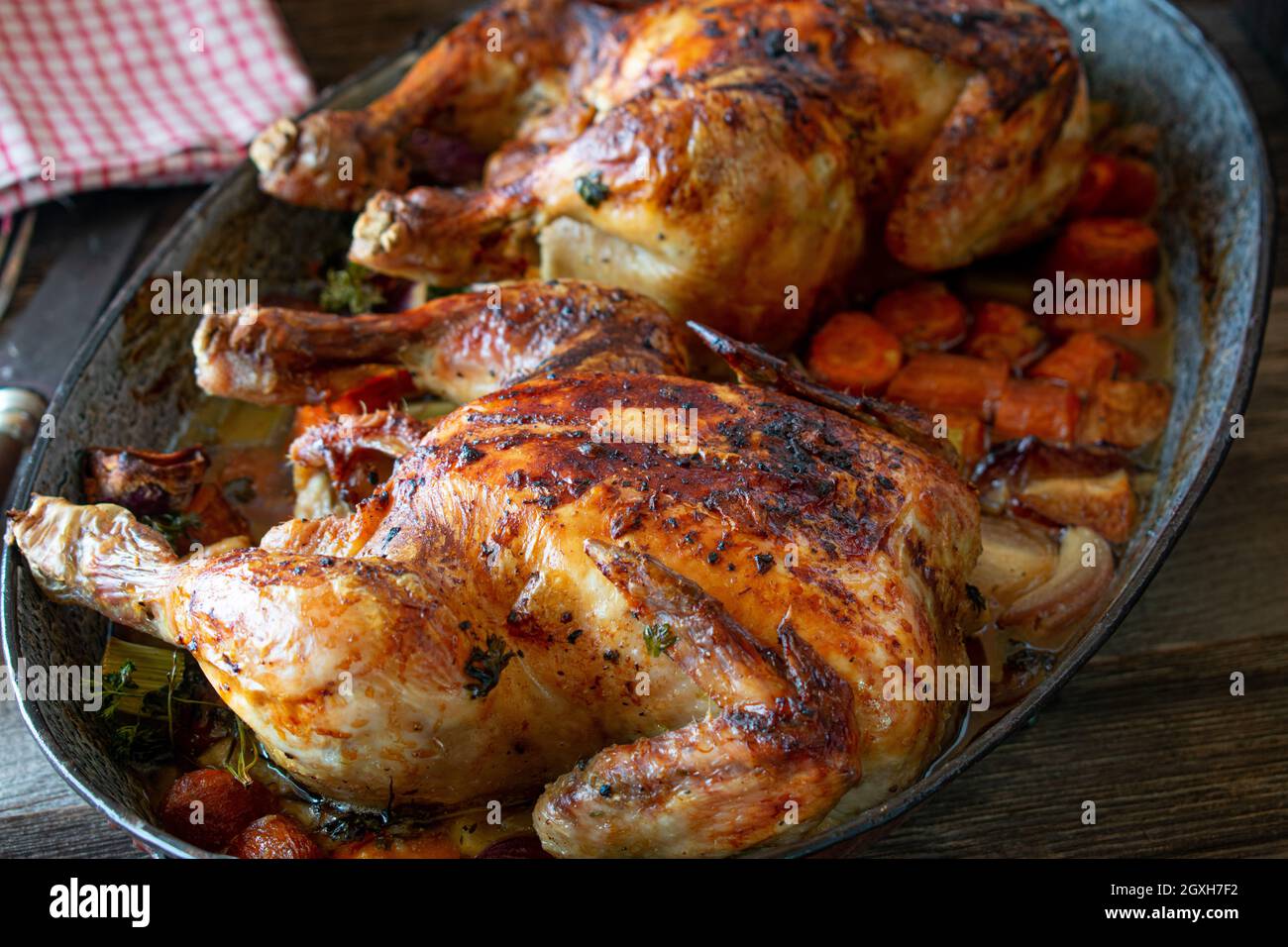 Hähnchen mit Wurzelgemüse in einer rustikalen Kasserolle rösten. Hausgemachte Mahlzeit isoliert auf rustikalen und Holztisch von oben Stockfoto