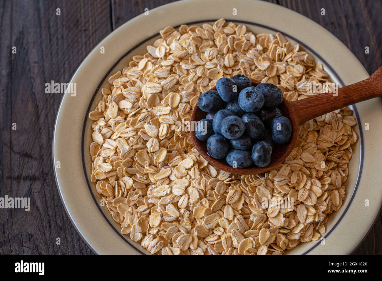Bio-Zutaten wie Haferflocken oder Haferflocken und frische Blaubeeren auf Holztisch Hintergrund. Gesunde Ernährung Konzept Stockfoto