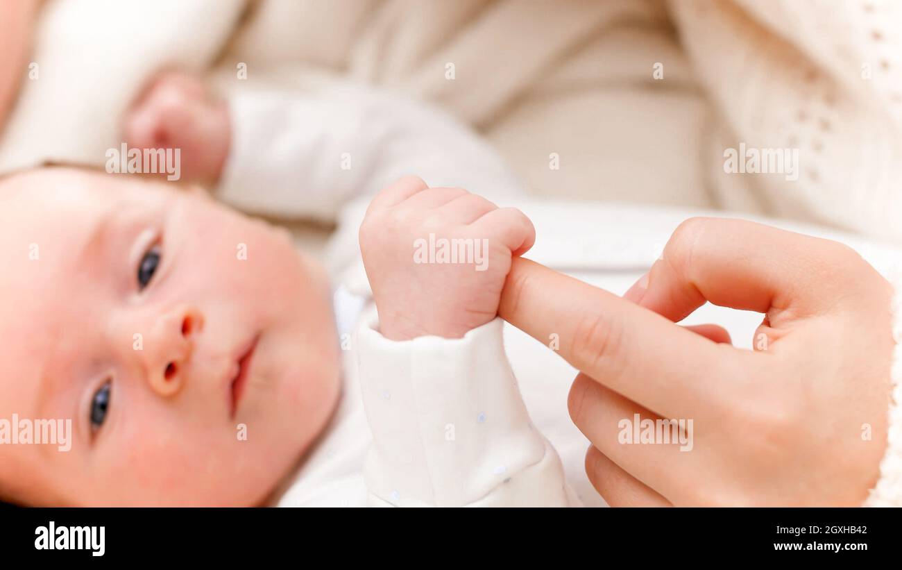 Nahaufnahme eines neugeborenen Jungen, der mit kleinen Händen den Finger der Mutter hält und fängt. Konzept von Familie Glück und liebevolle Eltern mit kleinen Kindern Stockfoto