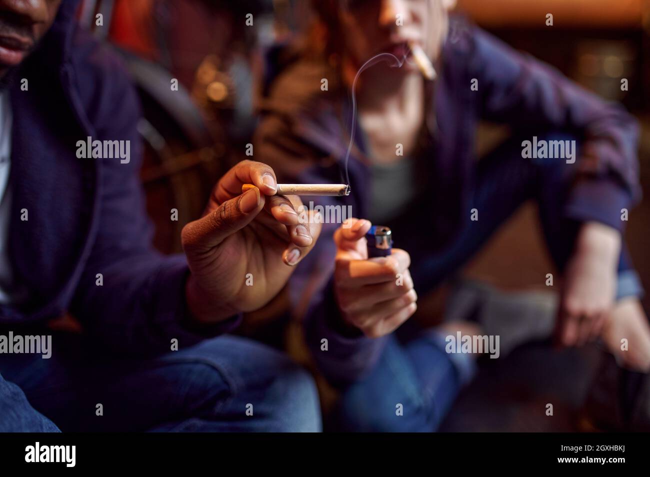 Drogensüchtiger Mann und Frau raucht eine Zigarette, während sie sich hoch in der Höhle befinden. Suchtproblem, ewige Depression von Junky-Leuten Stockfoto