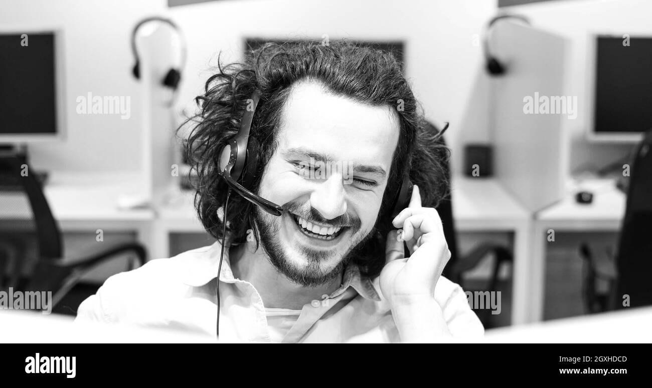 junge lächelnd männlichen Call Center-Betreiber macht seinen Job mit einem Kopfhörer Stockfoto