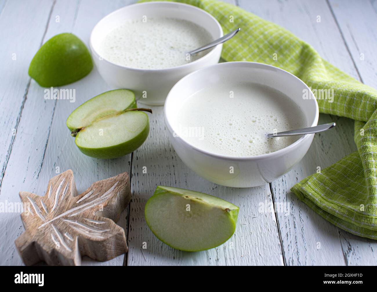 Hausgemachter frischer Bio-Joghurt mit grünen Äpfeln auf einem von oben isolierten weißen Holztisch. Weiches Gesundheitskonzept Stockfoto