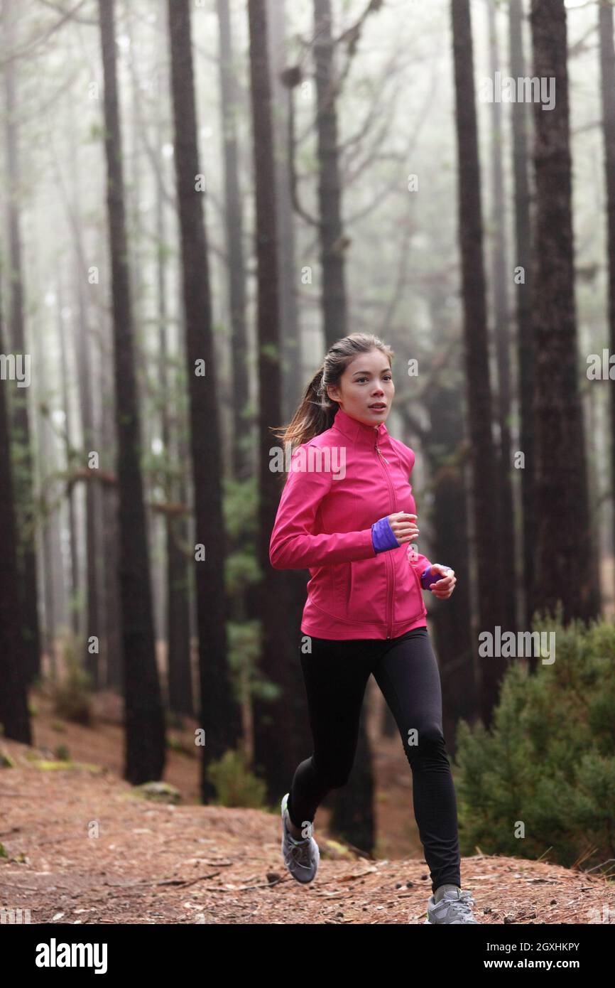 Trail Run FIT aktive asiatische Läuferin Frau beim Joggen im Wald am frühen Morgen im Nebel. Natur gesunde Bewegung im Freien vertikal des Mädchentrainings Stockfoto