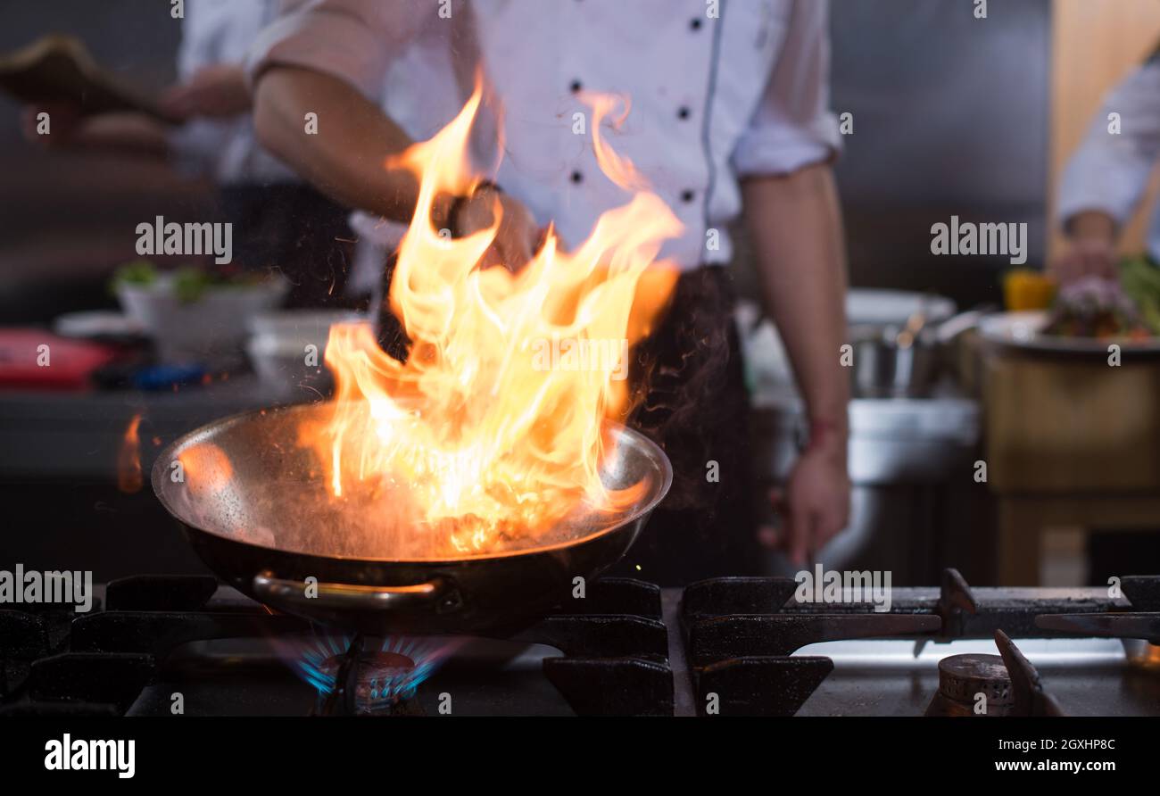 Küchenchef und flambiert auf Essen im Restaurant Küche Stockfoto