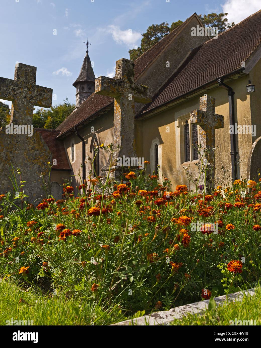 Blumen und Grabsteine auf dem Friedhof vor dem 12. Jahrhundert, Norman, St. Leonards Church, Hartley Mauditt, Hampshire, England, Großbritannien Stockfoto