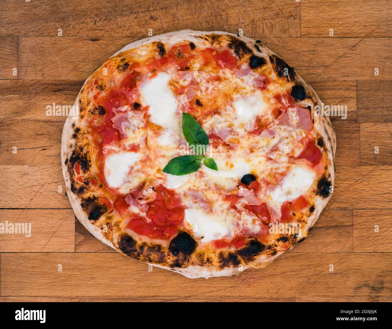 Hausgemachte neapolitanische Pizza auf rustikalem Holzbrett bereit zu essen. Leckere und leckere traditionelle italienische Pizza wenig an den Rändern verbrannt und ist bereit f Stockfoto