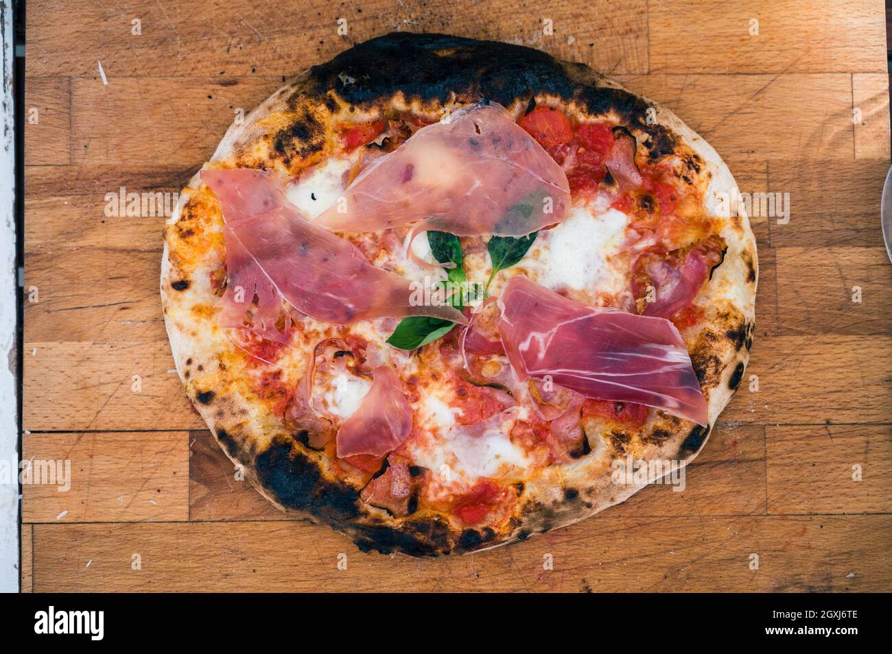 Hausgemachte neapolitanische Pizza auf rustikalem Holzbrett bereit zu essen. Leckere und leckere traditionelle italienische Pizza wenig an den Rändern verbrannt und ist bereit f Stockfoto