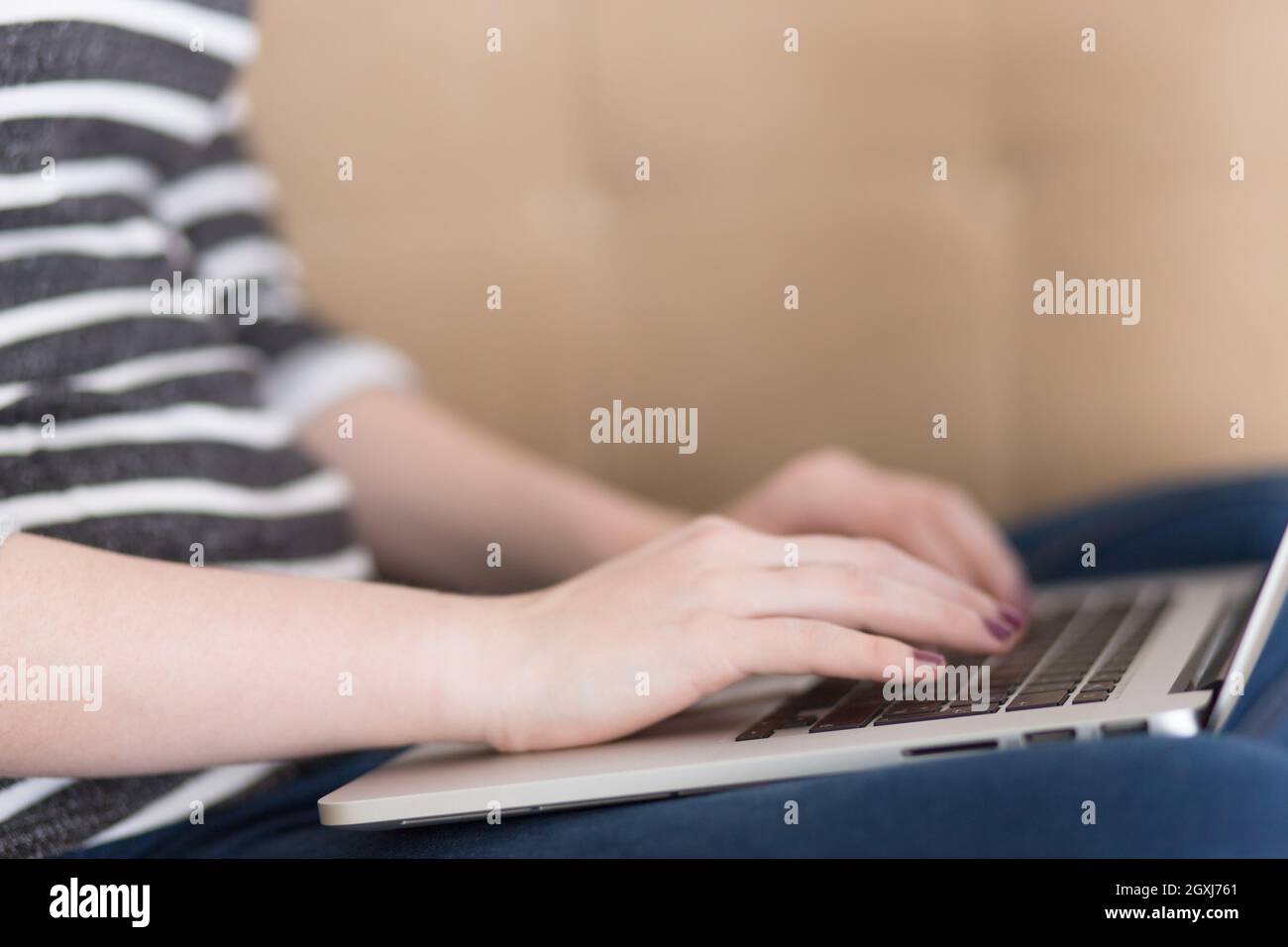 Schöne junge Frau auf dem Sofa zu Hause surfen Internet mit Laptop Stockfoto