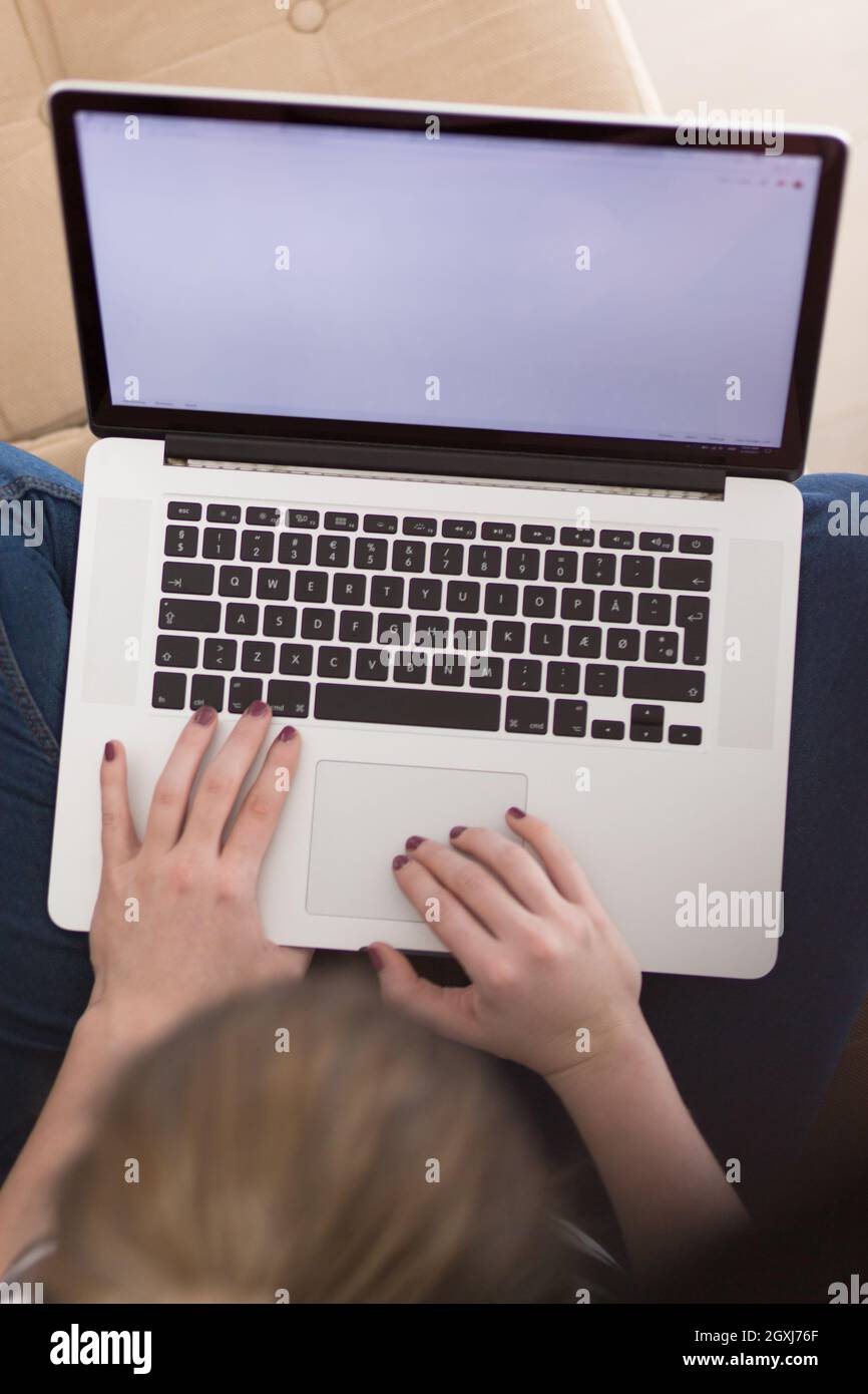 Schöne junge Frau auf dem Sofa zu Hause surfen Internet mit Laptop Stockfoto