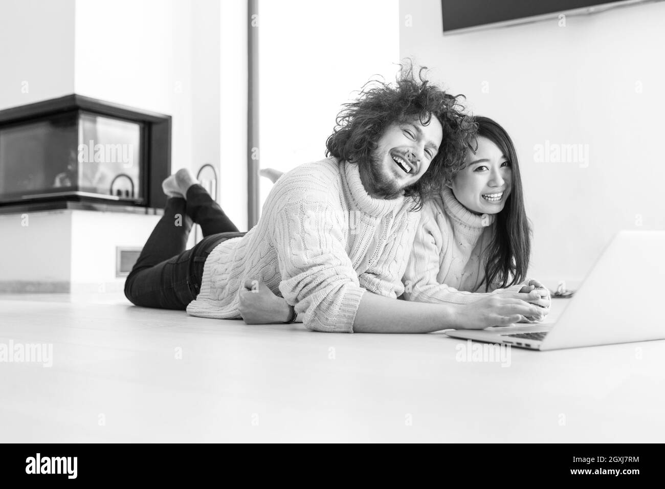 Junge schöne multiethnischen paar mit einem Laptop und Online-shopping zu Hause auf dem Boden Stockfoto