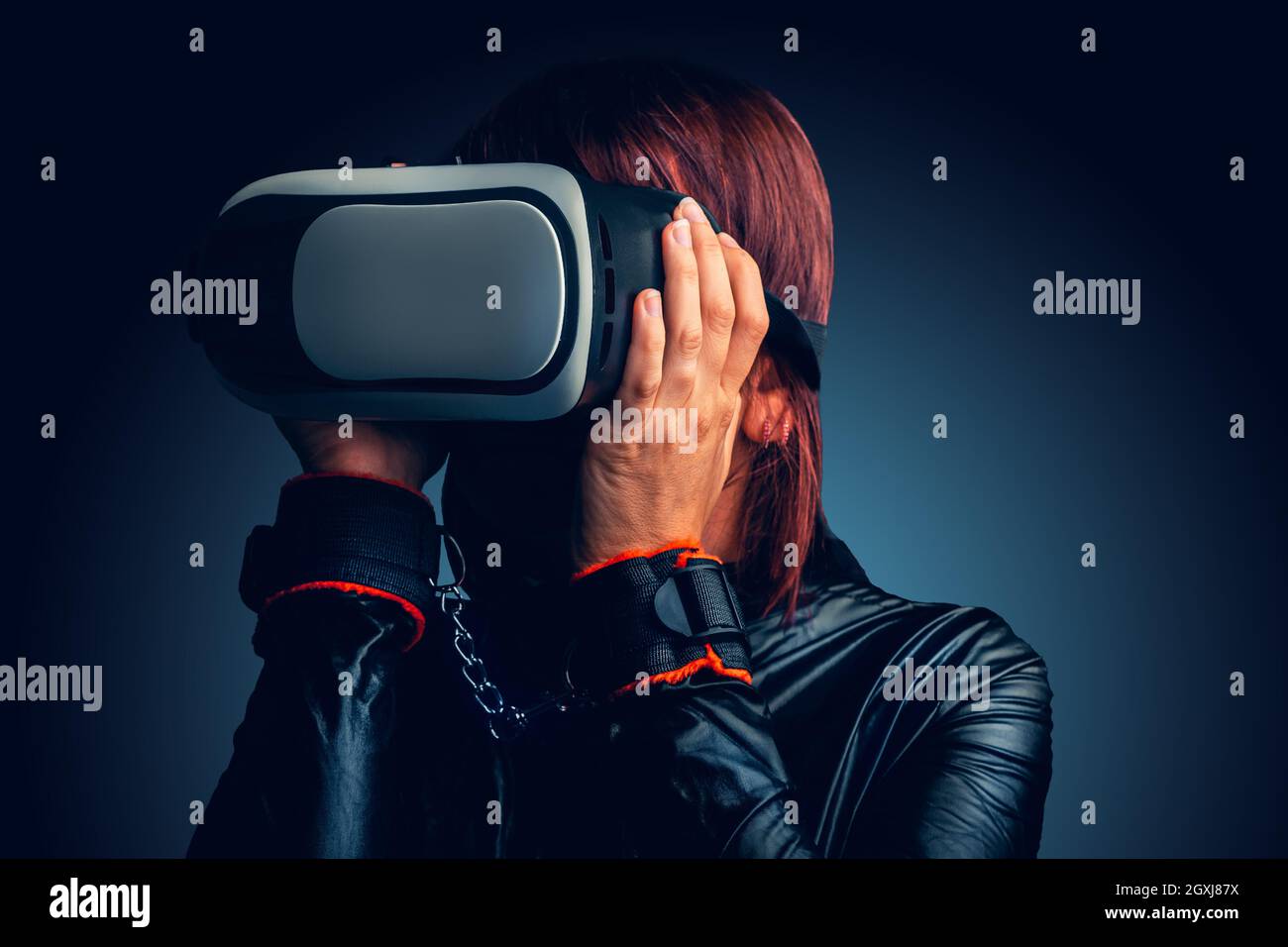 Sexy Frau mit Handschellen und Latexkleid genießen virtuelle Realität zu Hause. Konzept Virtuelle Liebe Stockfoto