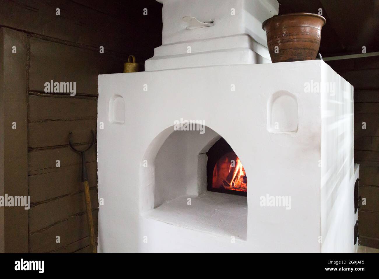 Ein großer russischer Ofen in einem Dorfhaus mit einem Tontopf Stockfotografie