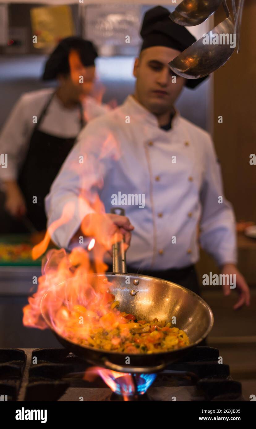 Küchenchef und flambiert auf Essen im Restaurant Küche Stockfoto