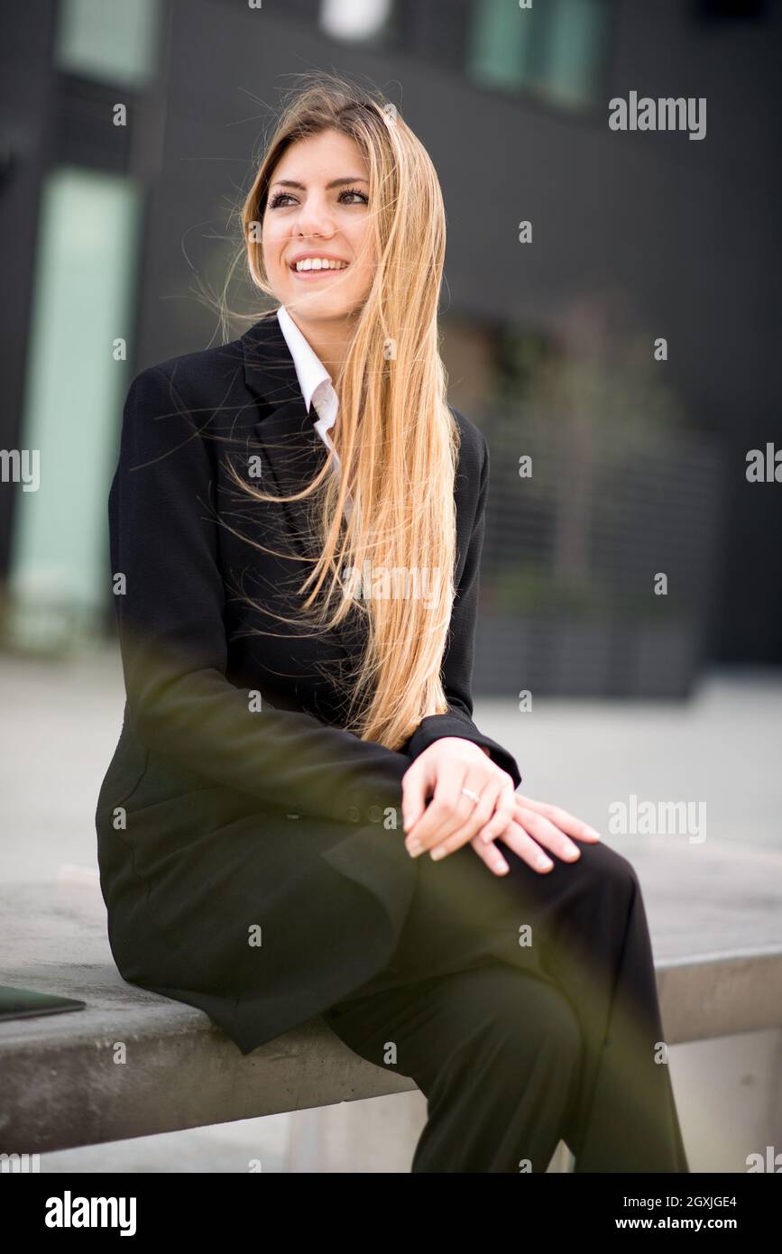 Junge Geschäftsfrau, die draußen auf einer Bank sitzt Stockfoto