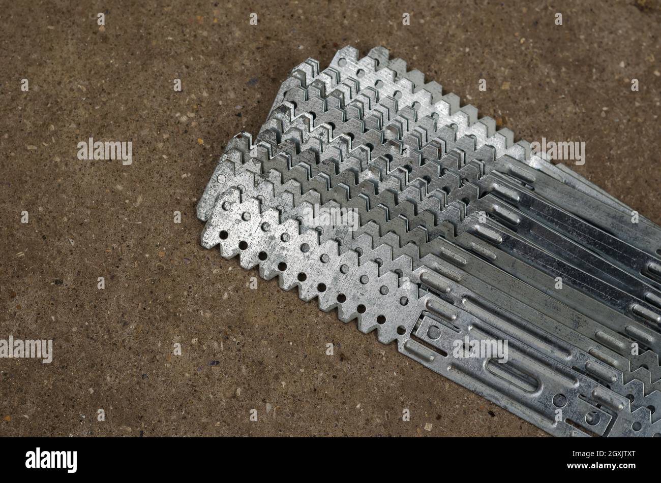 Gerader Aufhänger für Gipskarton. Trockenbauhalterungen. Lange Lochplatten sind aus verzinktem Stahl gefertigt. Vorrichtung für den Bau von Gipsplaste Stockfoto