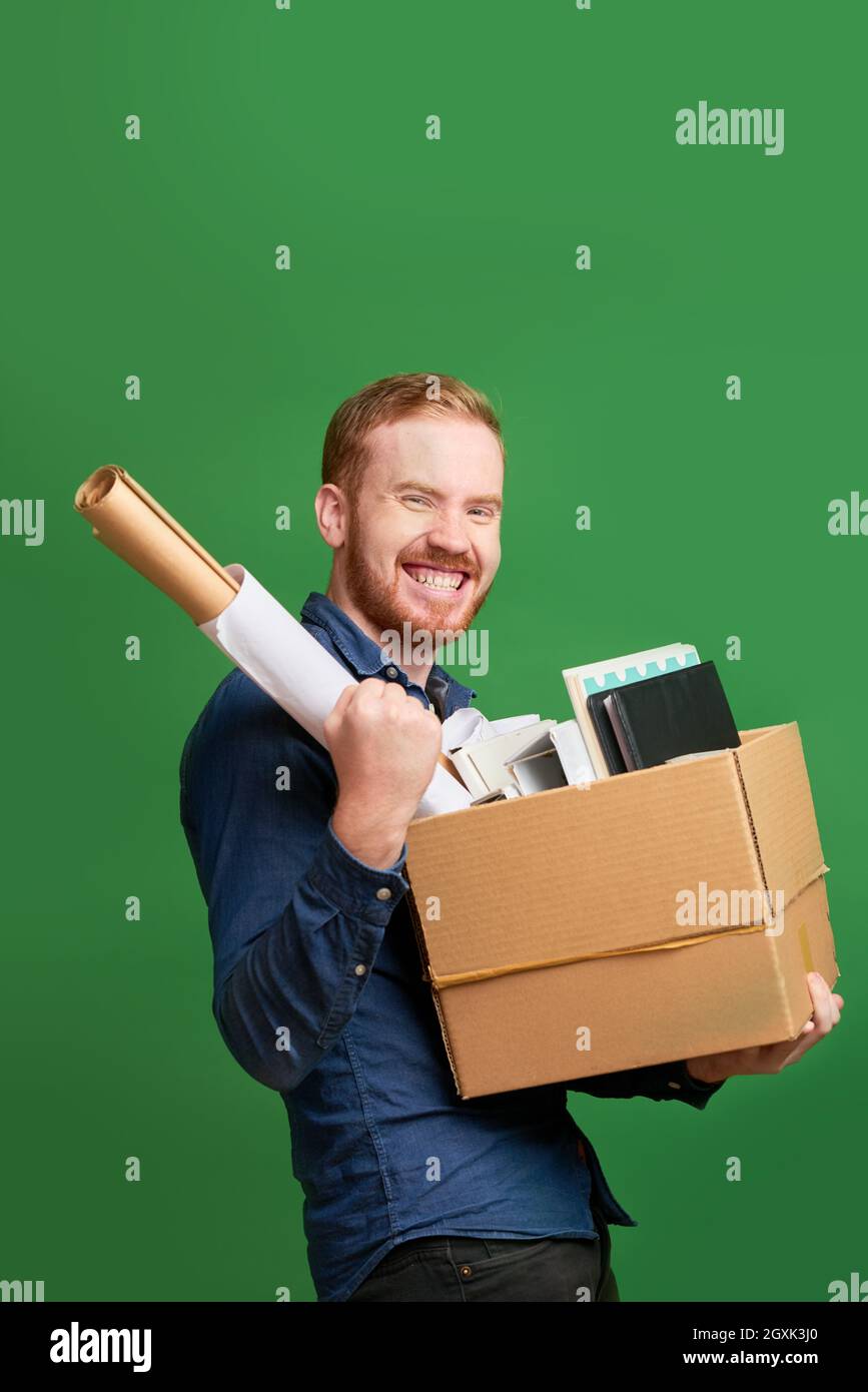 Porträt von fröhlich aufgeregt jungen kaukasischen Mann hält Stoff Box und macht ja Geste beim Wechsel des Arbeitsplatzes Stockfoto