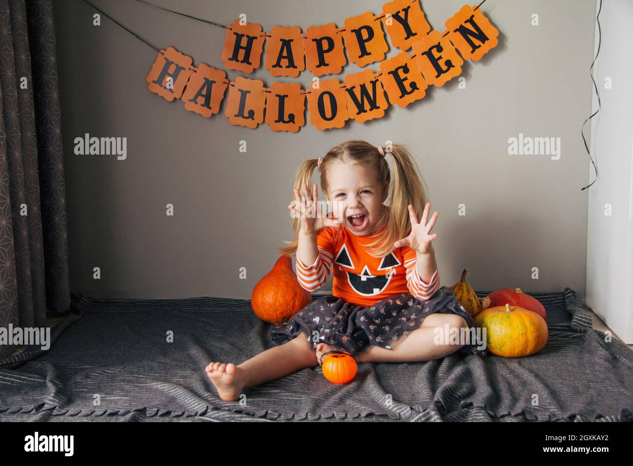 Ein kleines Mädchen in einem Kürbis Kostüm für Halloween, Trick or Treat. Kinder feiern Halloween. Das Mädchen ist bereit für den Trick or Treat Urlaub Stockfoto