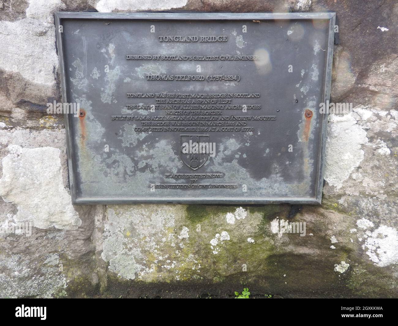 Plakette auf der Tongland Bridge in der Nähe von Kirkcudbright, Dumfries & Galloway, Schottland. Es wurde von Thomas Telford (1757-1834) entworfen. In der Nähe befindet sich das Wasserkraftwerk Tongland. Die Brücke war zum Zeitpunkt ihrer Errichtung die erste große in Schottland. Sie wurde in den Jahren 1804-8 erbaut und ersetzte eine ältere Brücke stromaufwärts und war die erste Brücke, die anstelle eines massiven Mauerbogens gewichtssparende hohle Rippenspandrels hatte. Obwohl die Bauweise wunderschön ist, kann die ganze Pracht nur von Spaziergängern auf dem nahe gelegenen Fußweg am Fluss geschätzt werden, wie man sie von der Straße über nicht in ihrer Gesamtheit sehen kann. Stockfoto