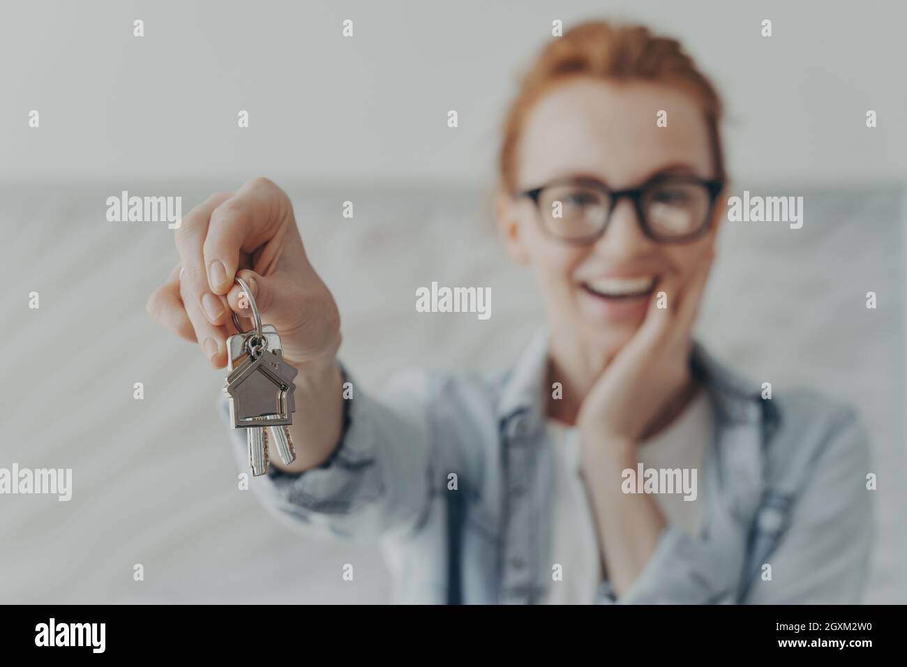 Glückliche weibliche Besitzerin der neuen Wohnung zeigt, dass Schlüssel froh Mieter oder Käufer sind Stockfoto