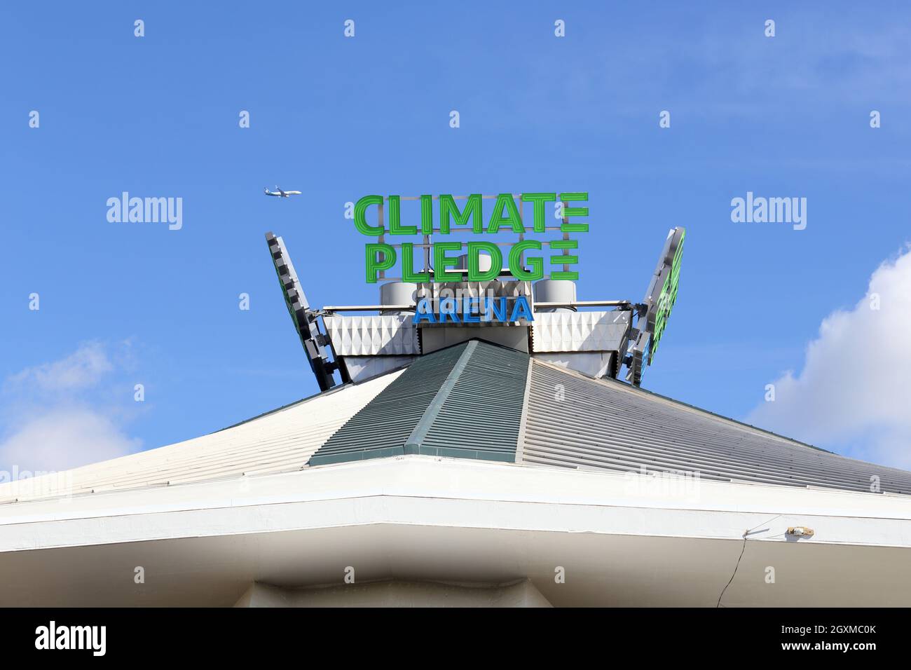 Ein Flugzeug fliegt über die Climate Pledge Arena im Seattle Center im Viertel Lower Queen Anne in Seattle, Washington. Stockfoto