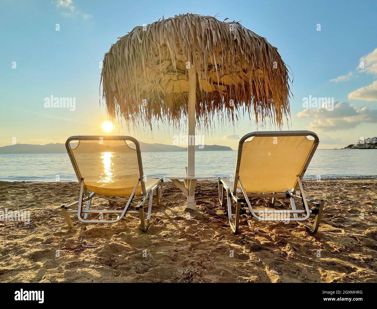 Zwei Sonnenliegen und ein Sonnenschirm am Strand, Skala, Agistri, Attica, Griechenland Stockfoto