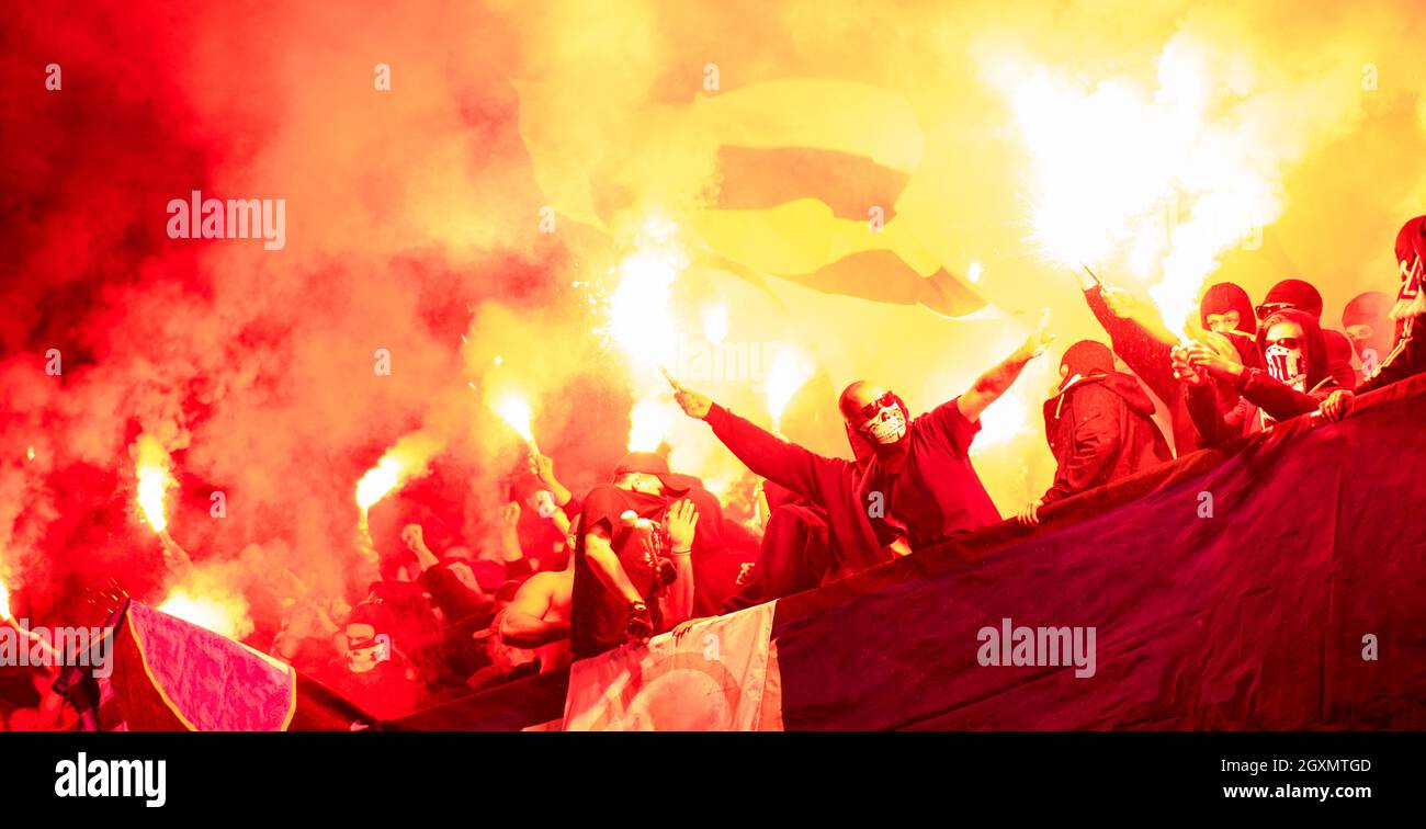 Fußball-Hooligans mit Maske halten Fackeln in Feuer, während Ihre Lieblingsmannschaft Unterstützung bei einem Spiel im Stadion Stockfoto