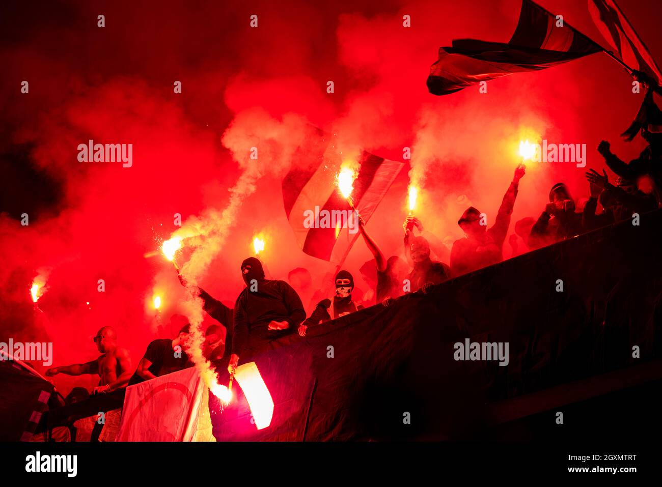 Fußball-Hooligans mit Maske halten Fackeln in Feuer, während Ihre Lieblingsmannschaft Unterstützung bei einem Spiel im Stadion Stockfoto
