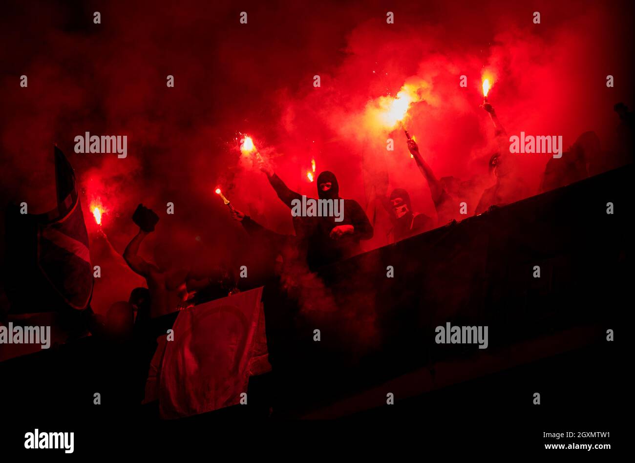 Fußball-Hooligans mit Maske halten Fackeln in Feuer, während Ihre Lieblingsmannschaft Unterstützung bei einem Spiel im Stadion Stockfoto