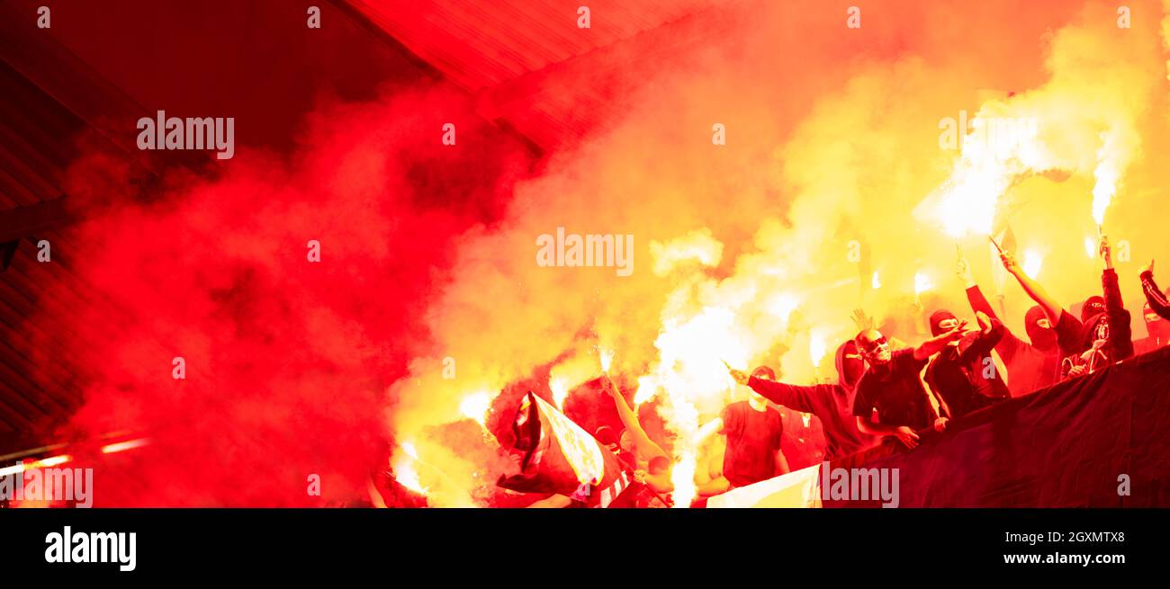 Fußball-Hooligans mit Maske halten Fackeln in Feuer, während Ihre Lieblingsmannschaft Unterstützung bei einem Spiel im Stadion Stockfoto