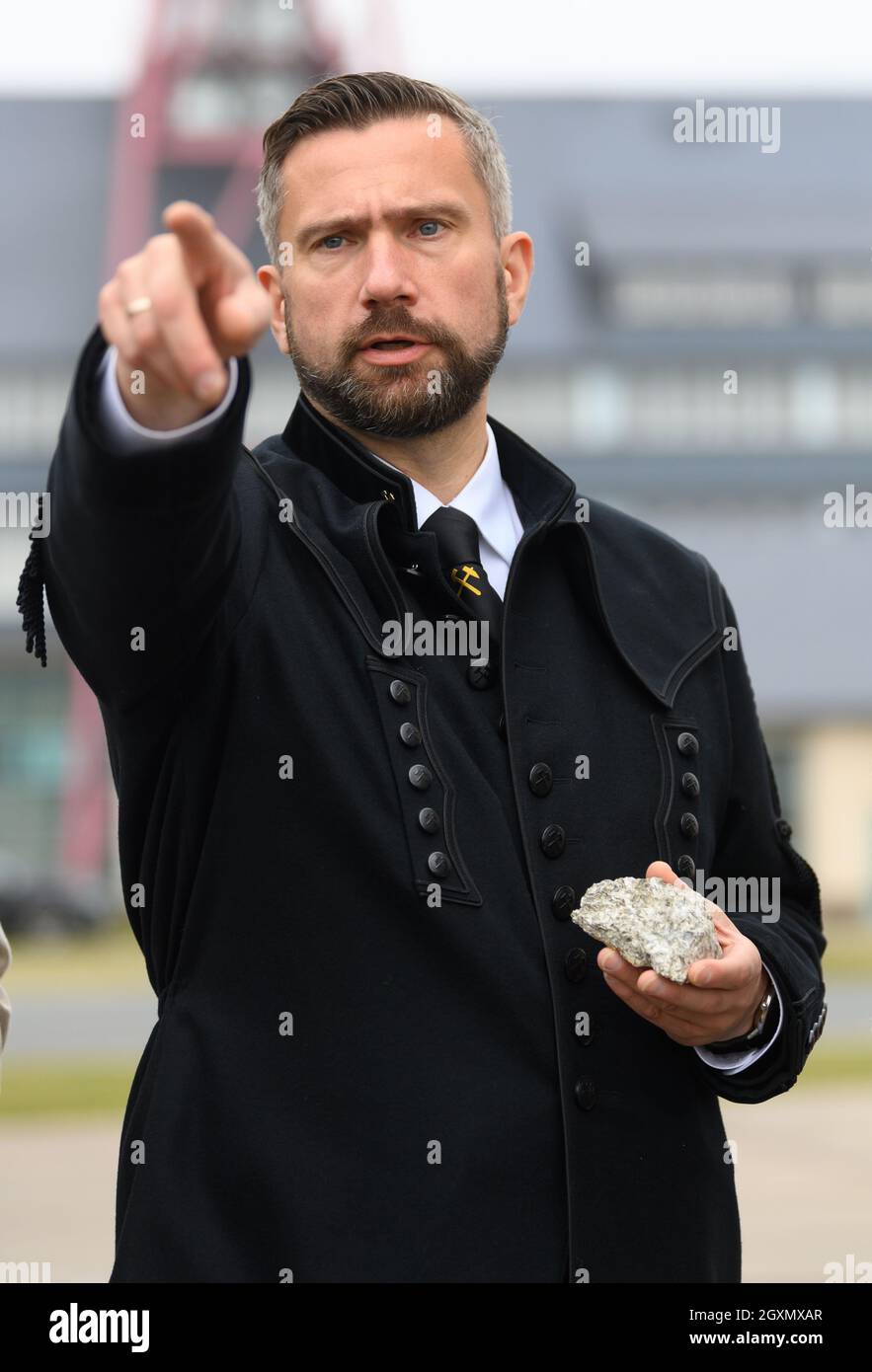 Altenberg, Deutschland. Oktober 2021. Der sächsische Wirtschaftsminister Martin Durig (SPD) steht während des "Rohstofftages" in einem Bergarbeiterkostüm vor dem Arno-Lippmann-Schacht und hält ein Stück Erz durstig mit Lithium. Um sich einen Eindruck von Sachsens Anteil an der zukünftigen Rohstoffgewinnung zu verschaffen, besucht der Wirtschaftsminister verschiedene Akteure. Kredit: Robert Michael/dpa/Alamy Live Nachrichten Stockfoto