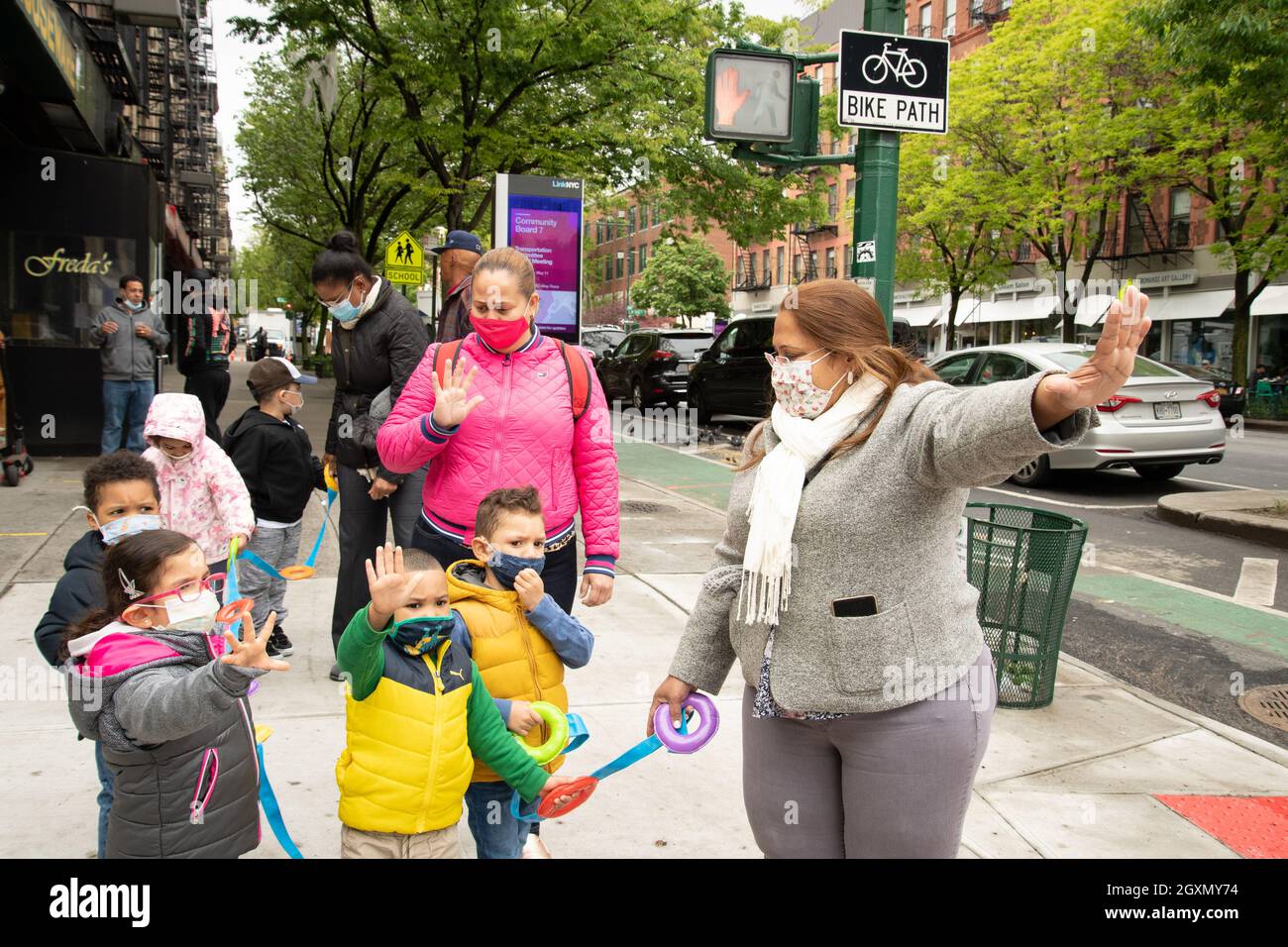Bildung Vorschulgruppe von 3-4-Jährigen auf einem Spaziergang eine Lehrerin, die die Hand hochhält, um mit Kindern, die sie imitieren, in Gesichtsmasken „aufzuhören“ Stockfoto