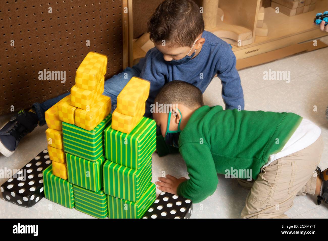 Bildung Vorschule 3-4-Jährige zwei Jungen, die mit bunten Schaumstoffblöcken im Blockbereich spielen und Gesichtsmasken tragen, um sich vor Covid-19 zu schützen Stockfoto