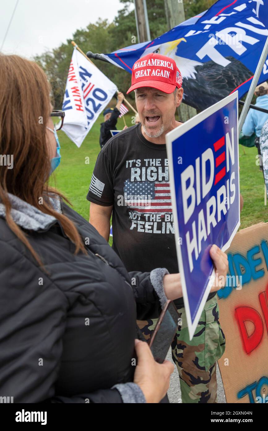 Howell, Michigan, USA. Oktober 2021. Die Republikaner protestieren, als Präsident Joe Biden Michigan besucht, um seinen Build Back Better Plan zu fördern. Ein Mann mit einem MAGA-Hut schreit eine Frau mit einem Pro-Biden-Zeichen an. Kredit: Jim West/Alamy Live Nachrichten Stockfoto