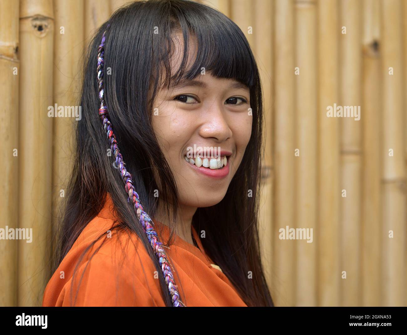Junge hübsche indonesische balinesische Masseurin mit langen Haaren lächelt und schaut den Betrachter an. Stockfoto