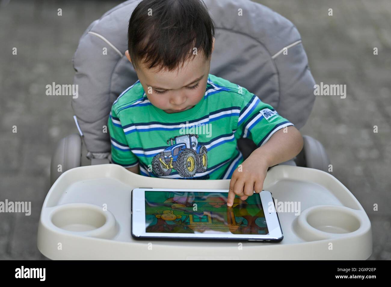 Kleinkind, 2 Jahre, multiethnisch, eurasisch, sitzt im Hochstuhl und spielt Lernspiel auf Tablet, Stuttgart, Baden-Württemberg, Deutschland Stockfoto