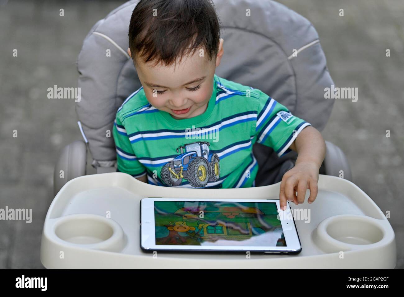 Kleinkind, 2 Jahre, multiethnisch, eurasisch, sitzt im Hochstuhl und spielt Lernspiel auf Tablet, Stuttgart, Baden-Württemberg, Deutschland Stockfoto