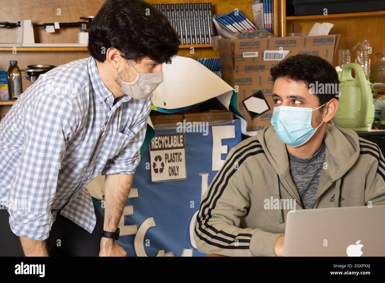 Bildung High School Klassenzimmer Szene, männlicher Lehrer hört männlichen Schüler, beide tragen Gesichtsmasken gegen Covid-19-Infektion zu schützen Stockfoto