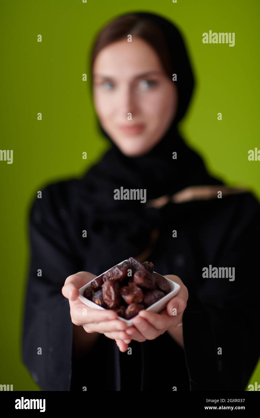 Moderne muslimische Frau in Abaya hält eine Dattefrucht und ein Glas Wasser von ihr. Konzept Feier des iftar im ramadan und Ende des Festes Stockfoto