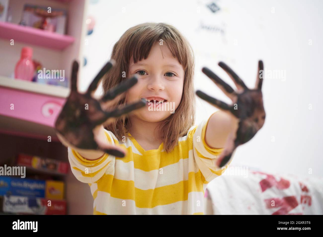 Nettes kleines Mädchen zu Hause Malerei mit Händen lustig kein Zahn Lächeln Stockfoto