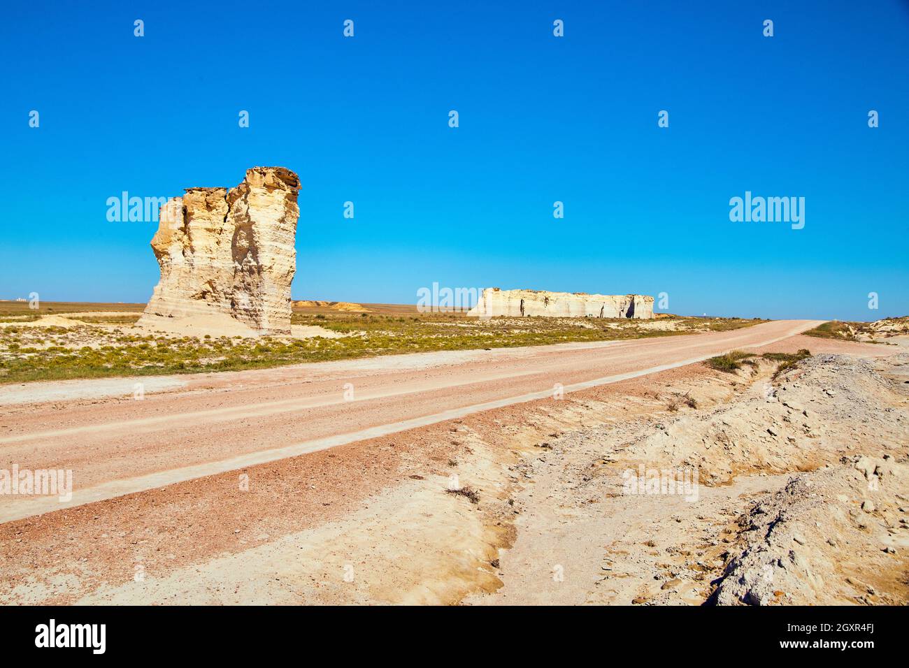 Unbefestigte Straße durch die flache Wüste mit Säulen aus weißem Felsen Stockfoto