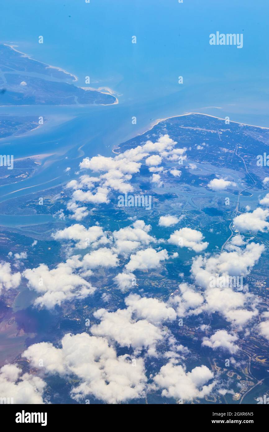 Flugzeugansicht von Land mit kleinen weißen Wolken und blauem Wasser Stockfoto