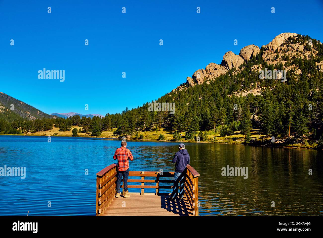Pier am See in den Bergen mit zwei Kindern und blauem Himmel Stockfoto