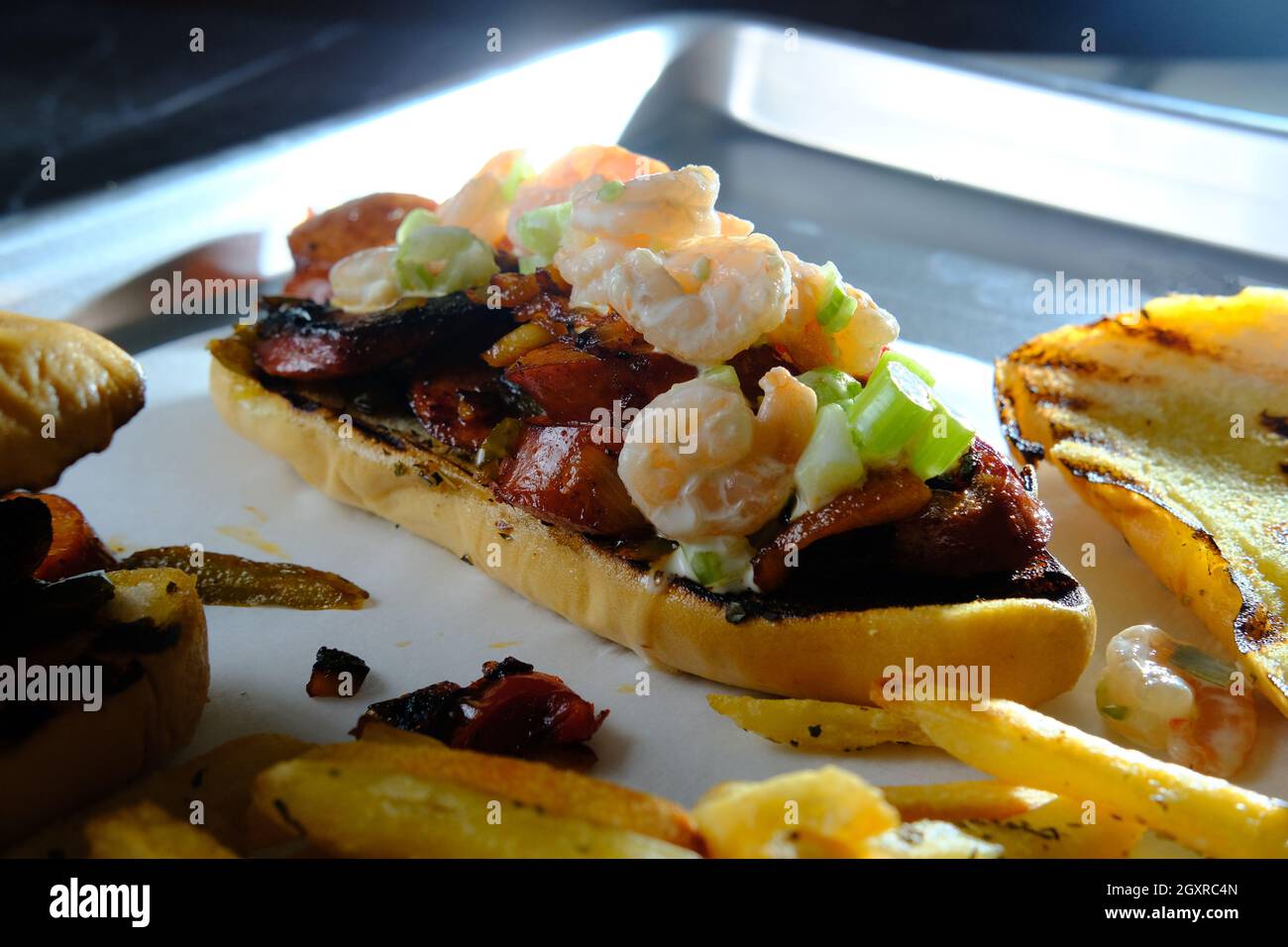 Wurst Zwiebeln und Paprika hoagie Sandwich mit Garnelensalat gekrönt ...